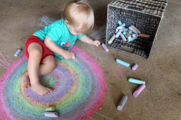 Małe dziecko maluje kredą kolorowe okręgi. 